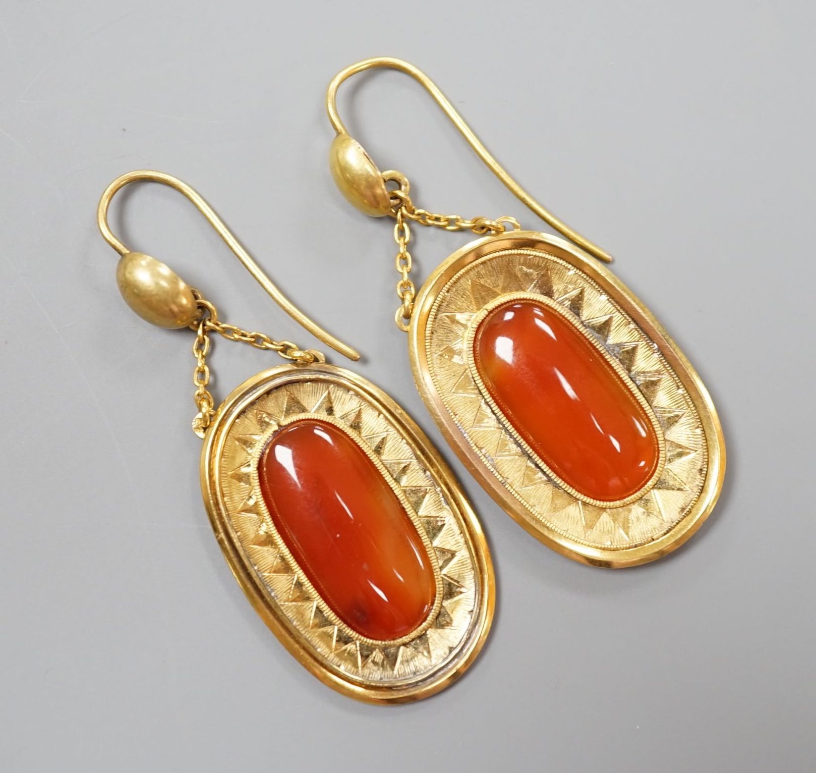 A pair of yellow metal and orange agate set oval drop earrings, overall 46mm, gross 6.8 grams.